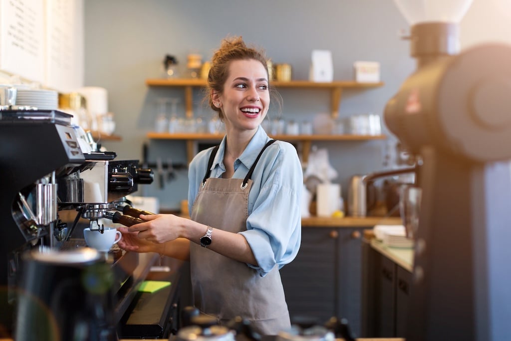 Barista smiling while making coffee in a modern cafe