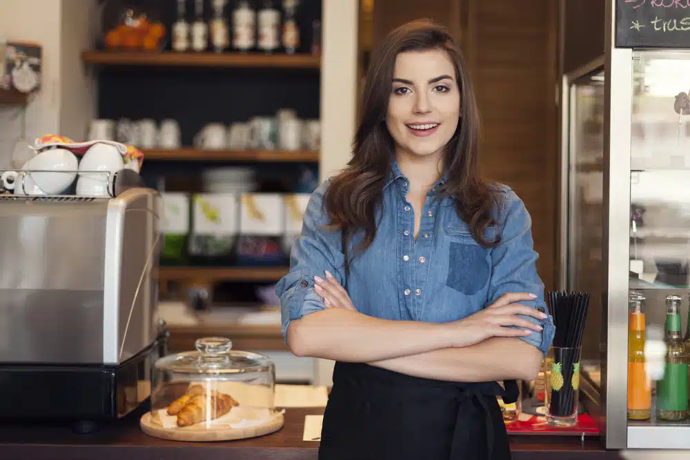 Young cafe owner standing confidently behind her counter
