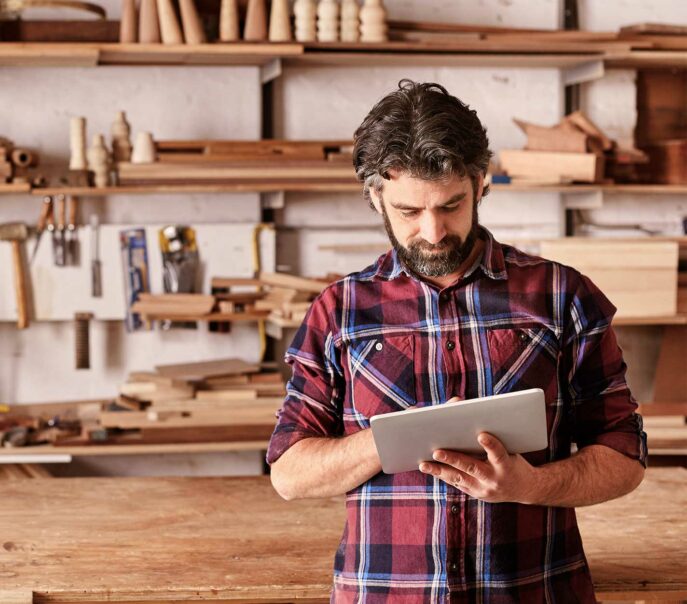 Man using a digital tablet in a woodworking workshop